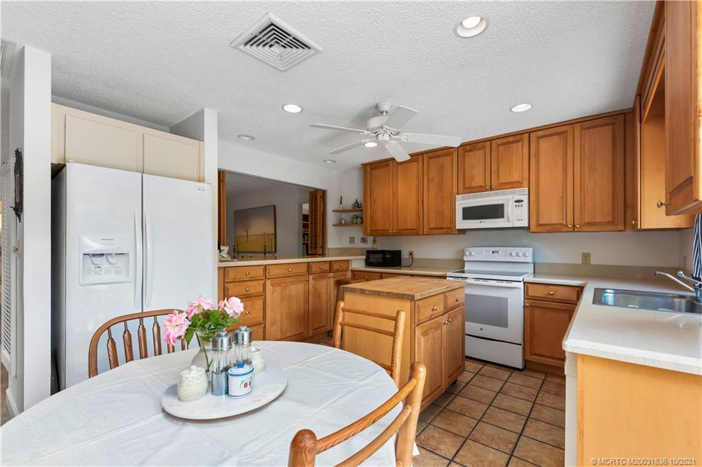 114 North Beach Road Hobe Sound, FL 33455 - Photo 21 of 37 a kitchen with stainless steel appliances kitchen island granite countertop a stove a sink a dining table and chairs