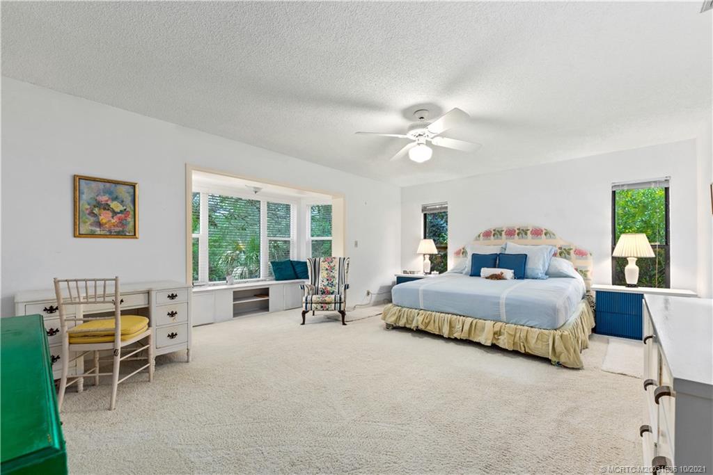 114 North Beach Road Hobe Sound, FL 33455 - Photo 25 of 37 a spacious bedroom with a bed a couch and a large window