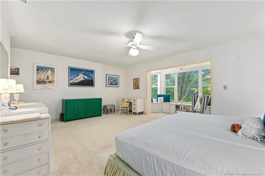 114 North Beach Road Hobe Sound, FL 33455 - Photo 26 of 37 a spacious bedroom with a bed a couch and a window