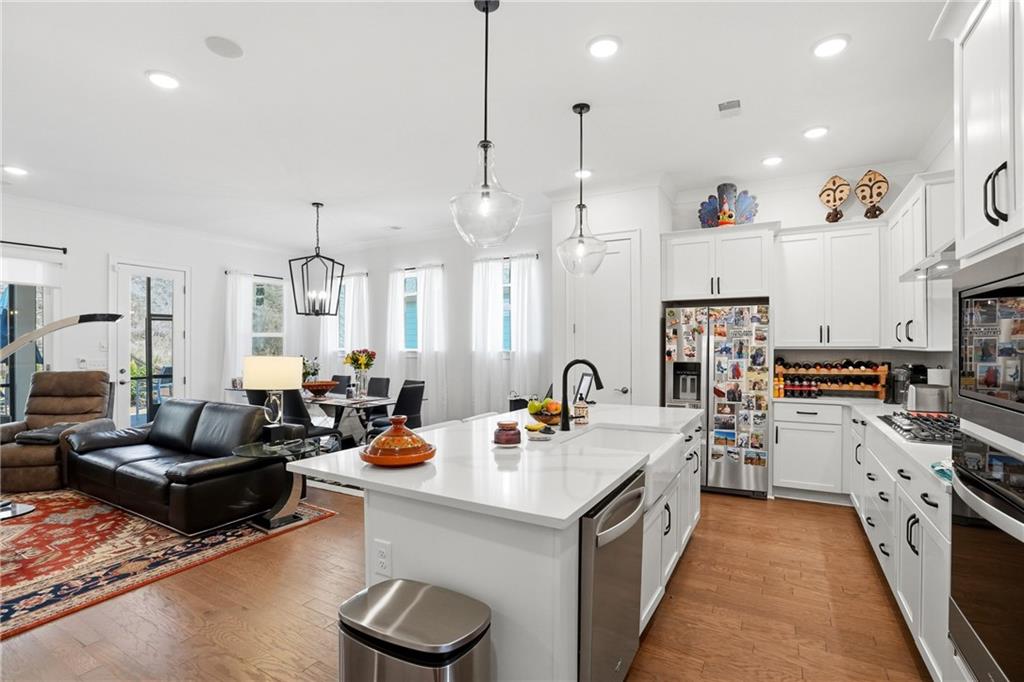 6742 Welcome Road Flowery Branch, GA 30542 - Photo 12 of 48 a open kitchen with stainless steel appliances kitchen island a white cabinets and wooden floor