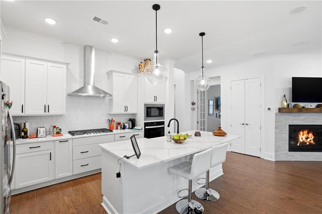 6742 Welcome Road Flowery Branch, GA 30542 - Photo 10 of 48 a kitchen with stainless steel appliances kitchen island granite countertop a sink a stove a dining table and chairs