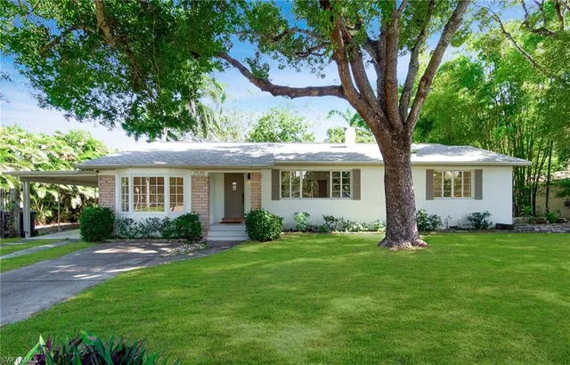 a front view of a house with a garden and trees