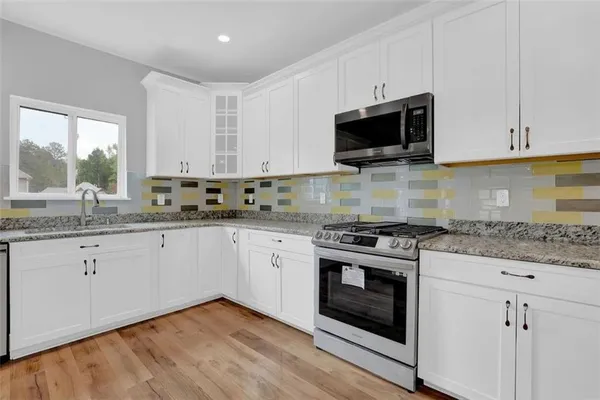 a kitchen with granite countertop white cabinets and a wooden floor