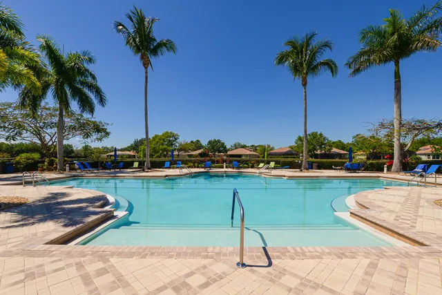 a view of pool with lawn chairs and iron fence