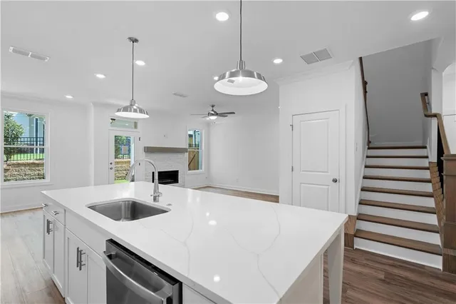 a large white kitchen with a sink a fireplace and wooden floor