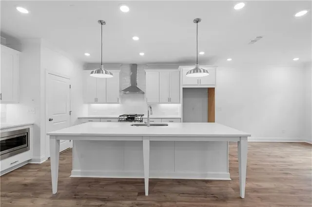 a large kitchen with kitchen island a stove a sink a center island and wooden floor