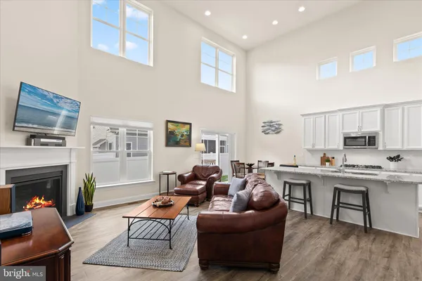 a kitchen with stainless steel appliances granite countertop a stove top oven a sink a refrigerator white cabinets and wooden floor