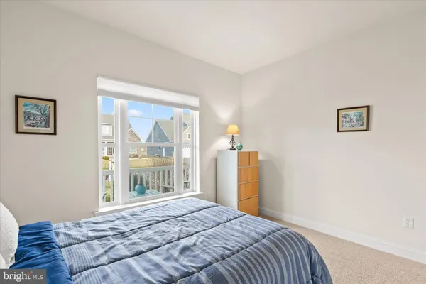 a bedroom with a bed dresser and a large window
