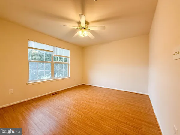 an empty room with wooden floor fan and windows