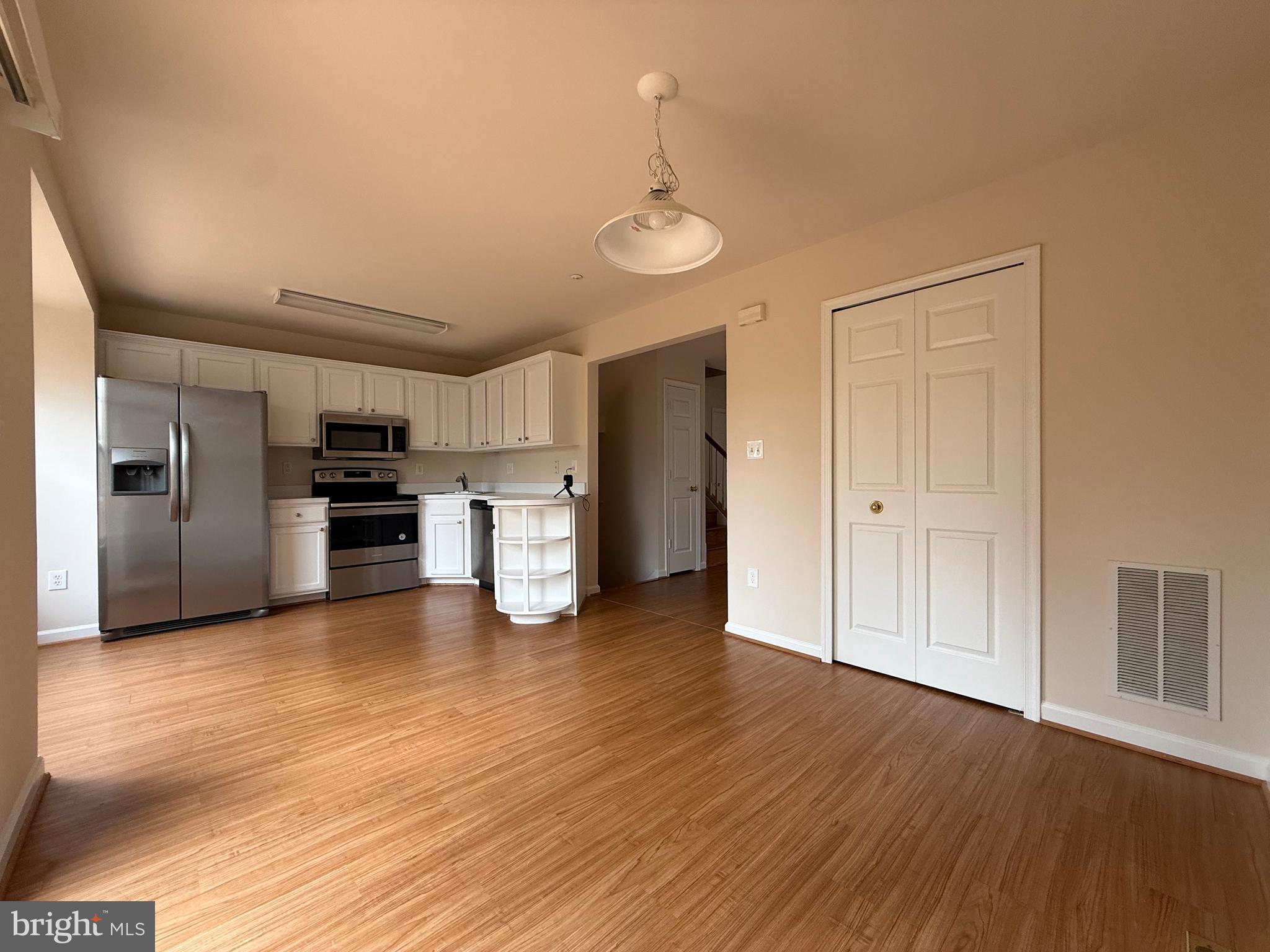 3511 Orchard Shade Road Randallstown, MD 21133 - Photo 6 of 30 a view of a kitchen with a refrigerator a stove top oven cabinets and wooden floor