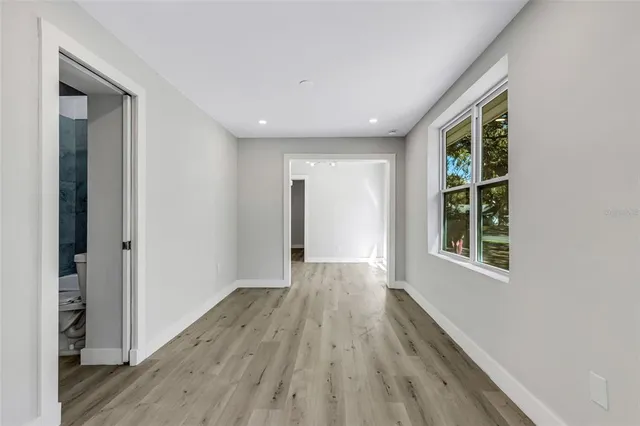 a view of an empty room with wooden floor and a window