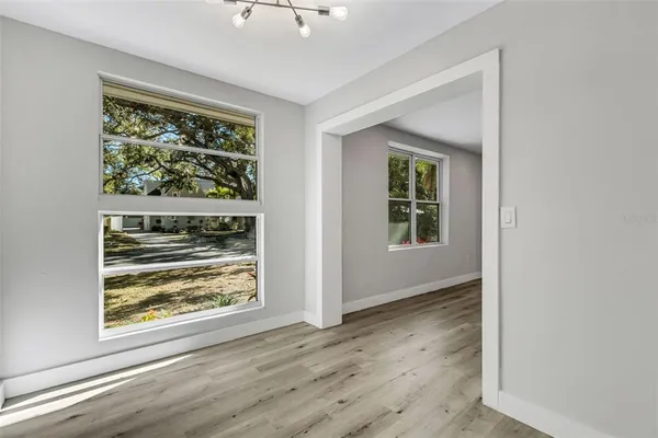an empty room with wooden floor cabinet and windows