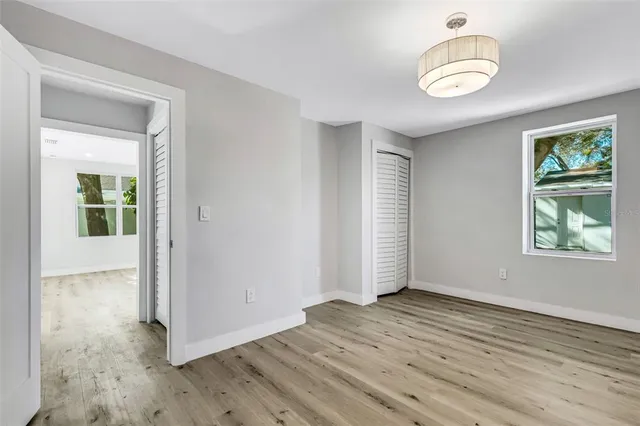 an empty room with wooden floor cabinet and windows