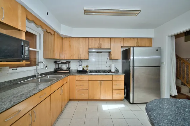 a kitchen with granite countertop a refrigerator a sink a stove top oven and cabinets