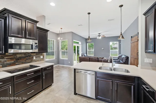 a kitchen with stainless steel appliances granite countertop a sink a stove and a wooden floors