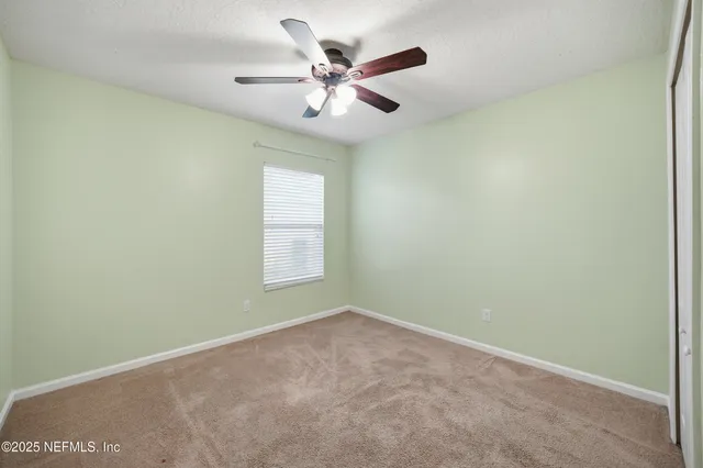 an empty room with a ceiling fan and window