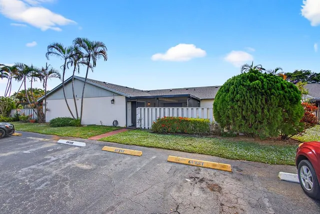 a view of a house with a yard and palm trees