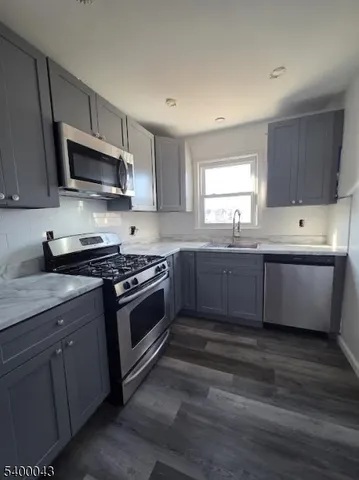 a kitchen with stainless steel appliances kitchen island granite countertop a sink dishwasher a stove and a microwave oven with cabinets