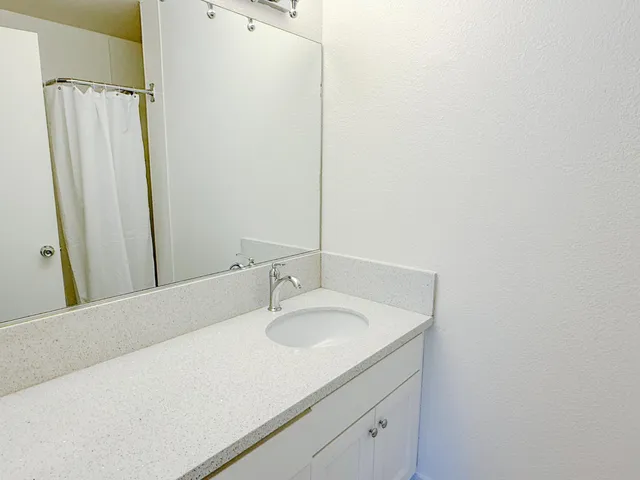 a bathroom with a granite countertop sink a mirror and a picture on the wall