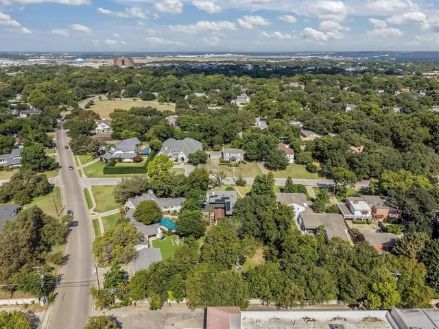 an aerial view of residential houses with outdoor space and trees
