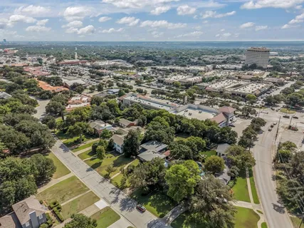 an aerial view of a residential houses with outdoor space and trees