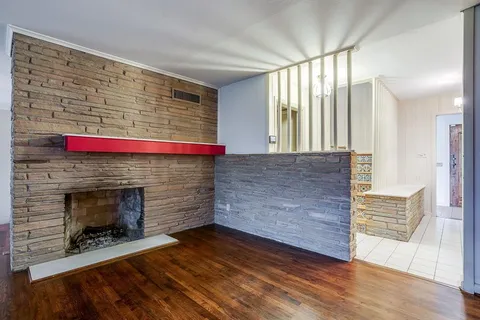 a living room with stainless steel appliances wooden floor and a fireplace