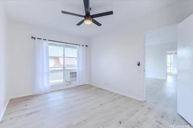 an empty room with wooden floor fan and windows