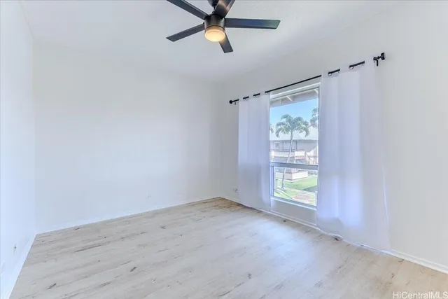 an empty room with windows and ceiling fan