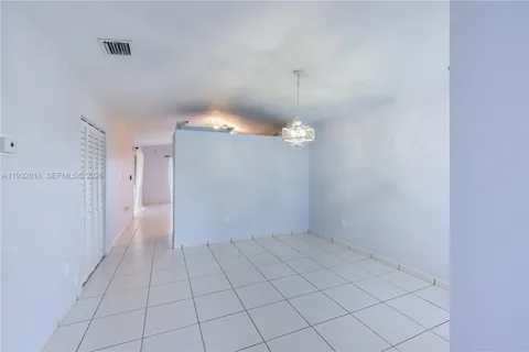 a view of an empty room and a chandelier fan