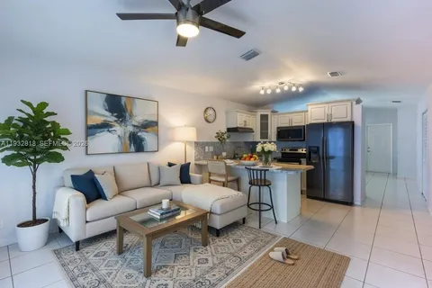a living room with furniture kitchen view and a potted plant