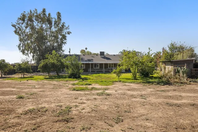a view of a house with a big yard and palm trees