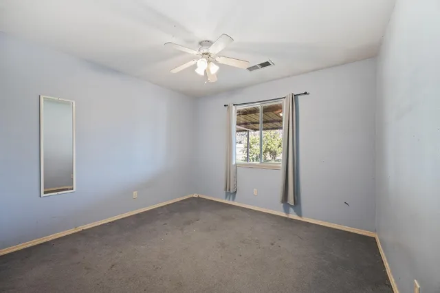 an empty room with windows and fan
