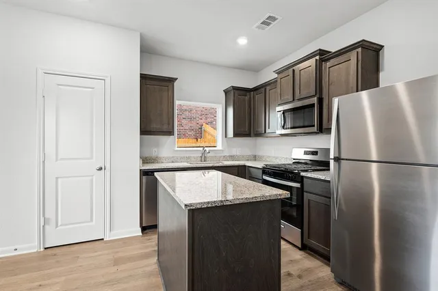 a kitchen with granite countertop a refrigerator stove and sink