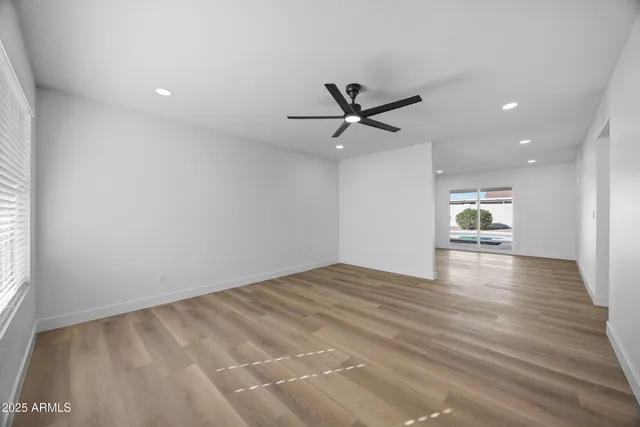 a view of empty room with wooden floor and fan