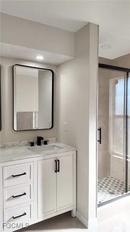 a bathroom with a granite countertop sink a mirror and shower