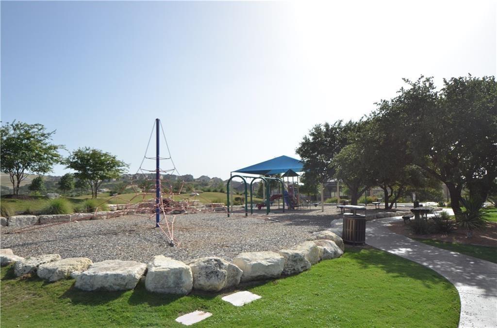 5629 Rio Chama Cove Austin, TX 78738 - Photo 29 of 34 A community playground features climbing structures, shaded play areas, and mature trees, ideal for recreation.
