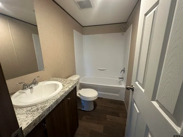 a bathroom with a granite countertop sink toilet and shower