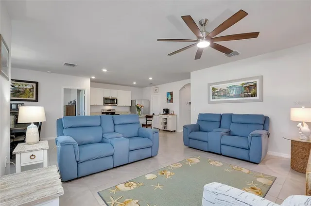 a kitchen with stainless steel appliances granite countertop a stove a sink a refrigerator a dining table and chairs with wooden floor