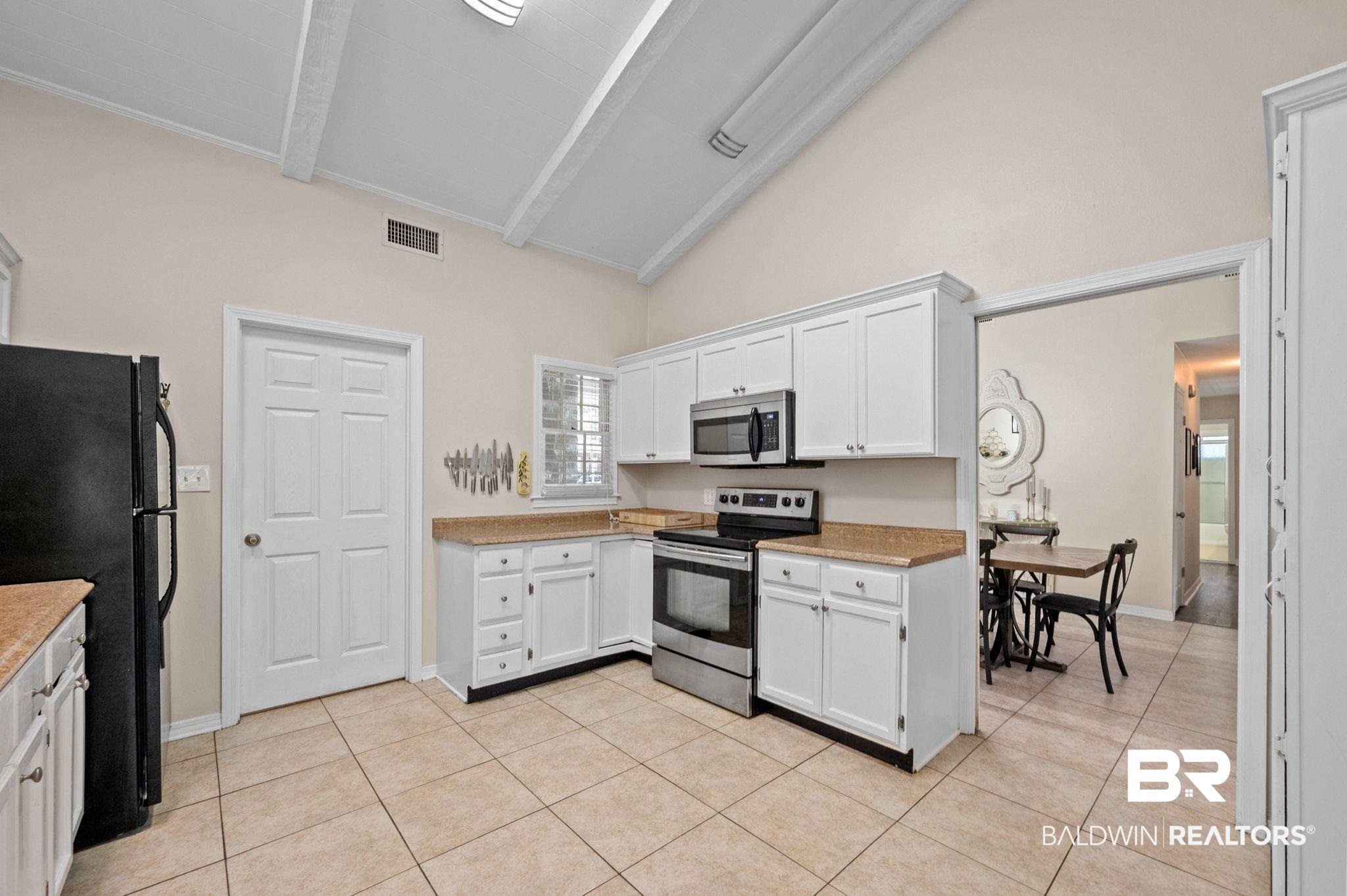 110 Ferncliff Circle Daphne, AL 36526 - Photo 15 of 40 Kitchen with stainless steel appliances, high vaulted ceiling, light tile patterned floors, white cabinetry, and beam ceiling
