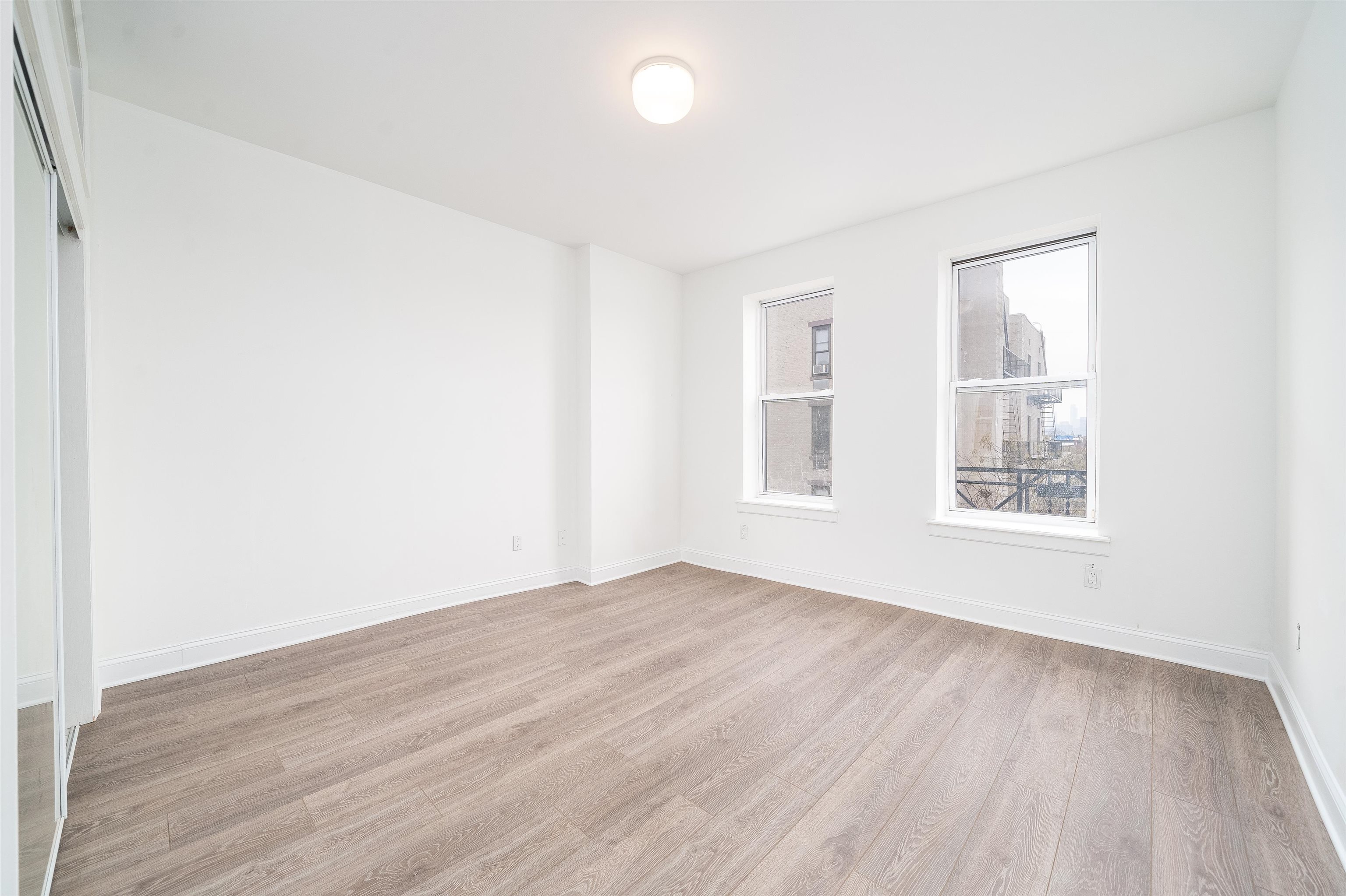 157 14th Street, Unit 5L Hoboken, NJ 07030 - Photo 7 of 11 an empty room with wooden floor and windows