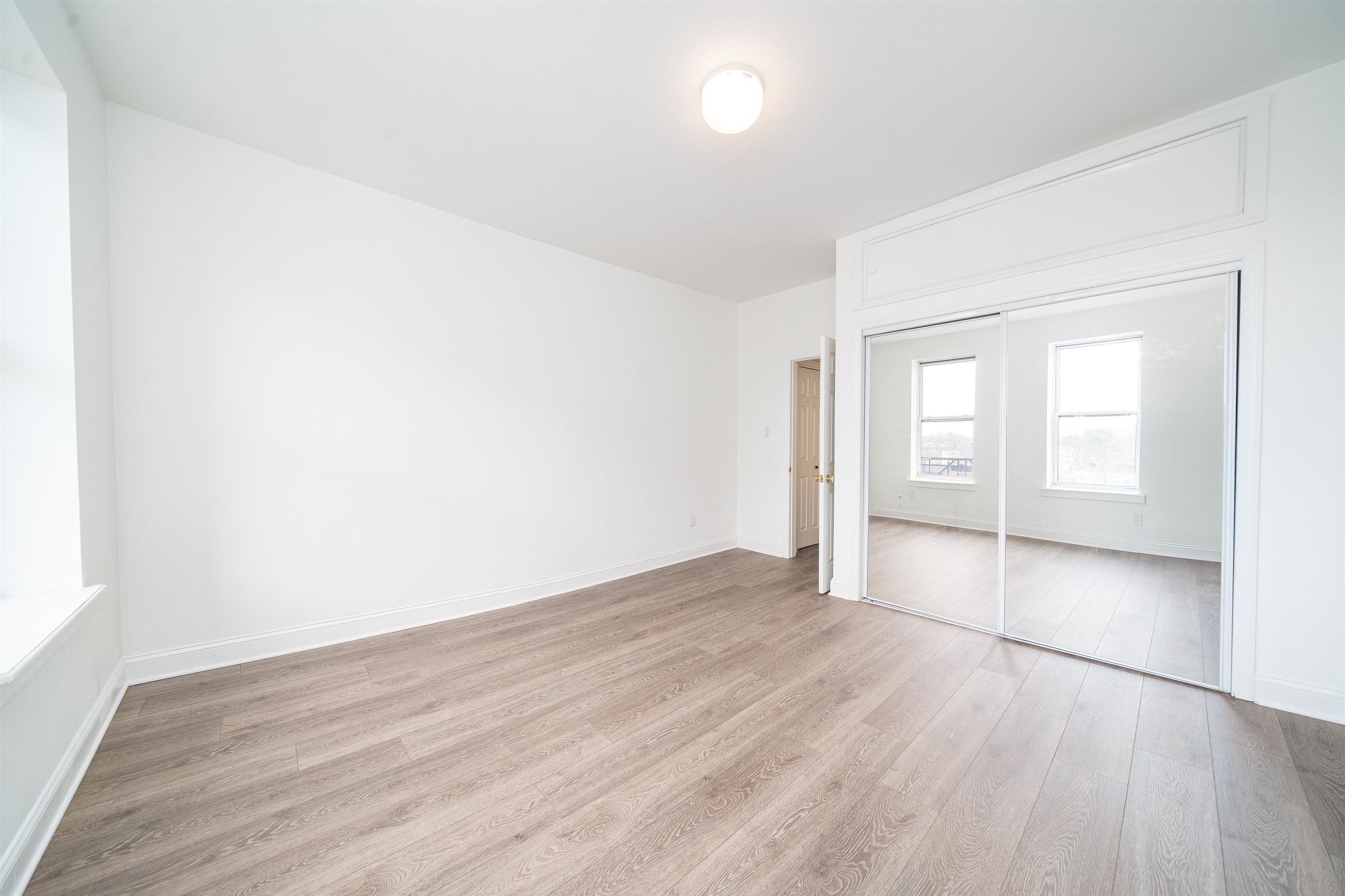 157 14th Street, Unit 5L Hoboken, NJ 07030 - Photo 9 of 11 an empty room with wooden floor and windows
