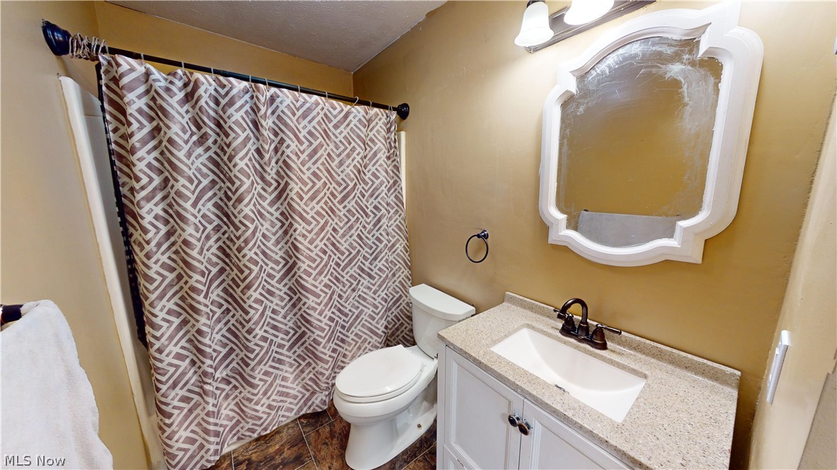 6970 Bushnell Road Conneaut, OH 44030 - Photo 19 of 28 Bathroom with vanity, toilet, a textured ceiling, and tile floors