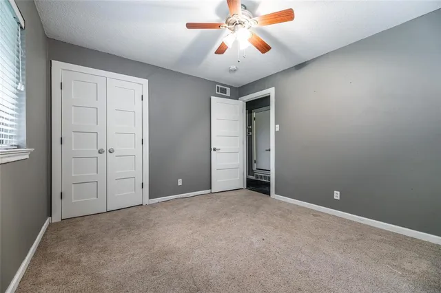 an empty room with windows and fan