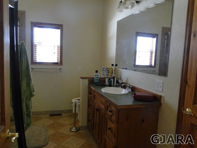 2501 Riata Ranch Road Grand Junction, CO 81505 - Photo 12 of 16 a bathroom with a granite countertop sink a mirror and a window