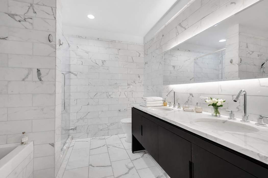 225 5th Avenue, Unit 6R Manhattan, NY 10010 - Photo 5 of 8 a bathroom with a granite countertop sink a mirror and shower