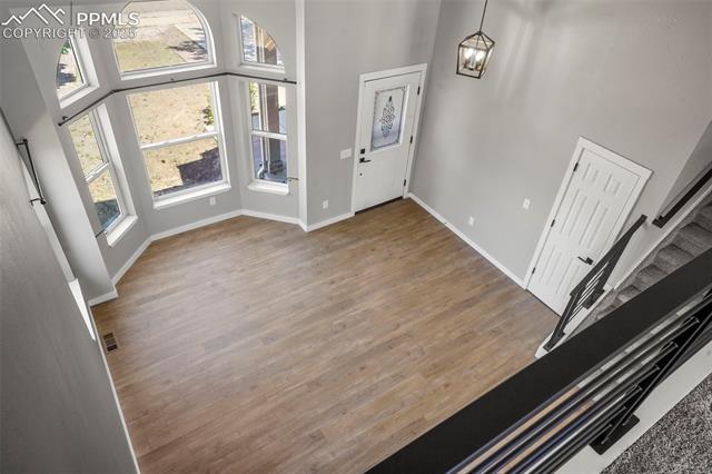 8035 Ferguson Road Peyton, CO 80831 - Photo 20 of 28 Entrance foyer with a wealth of natural light, hardwood / wood-style floors, a towering ceiling, and an inviting chandelier