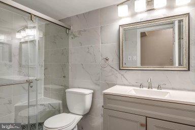11232 Chestnut Grove Square, Unit 20 Reston, VA 20190 - Photo 29 of 40 a bathroom with a granite countertop toilet sink shower and mirror