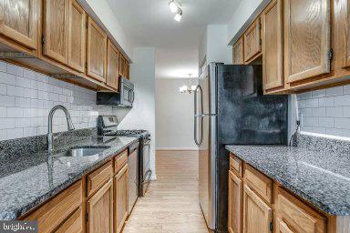 11232 Chestnut Grove Square, Unit 20 Reston, VA 20190 - Photo 8 of 40 a kitchen with stainless steel appliances granite countertop a sink a stove and a wooden cabinets