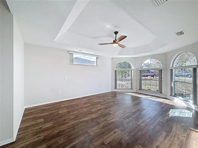 a view of an empty room with window and wooden floor
