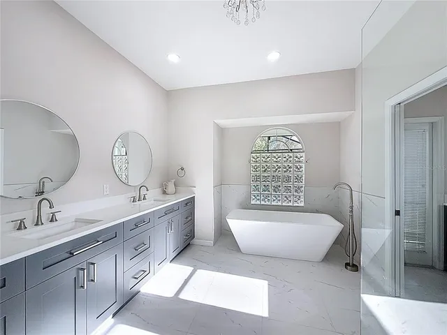 a spacious bathroom with double vanity a mirror a bathtub and a sink